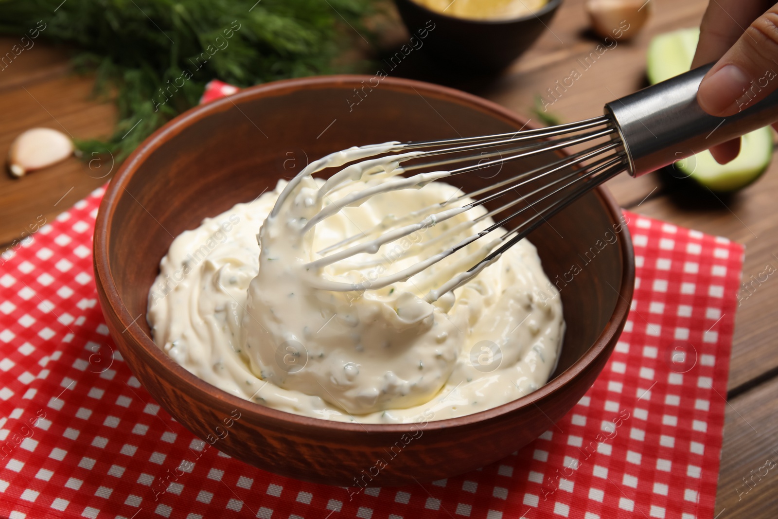 Photo of Woman making delicious tartar sauce at wooden table, closeup