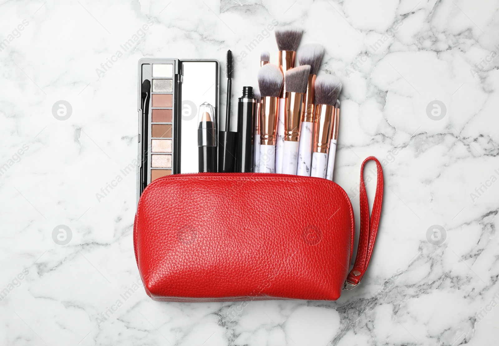 Photo of Cosmetic bag with makeup products and beauty accessories on white marble background, flat lay