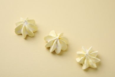 Delicious meringue cookies on beige background, above view