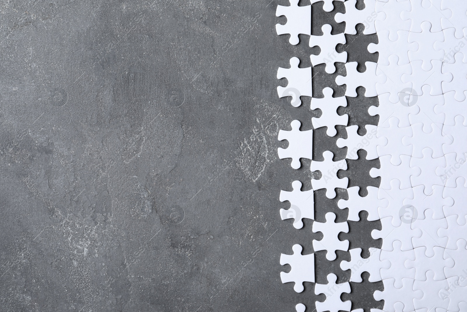 Photo of Blank white puzzle pieces on grey stone background, flat lay. Space for text