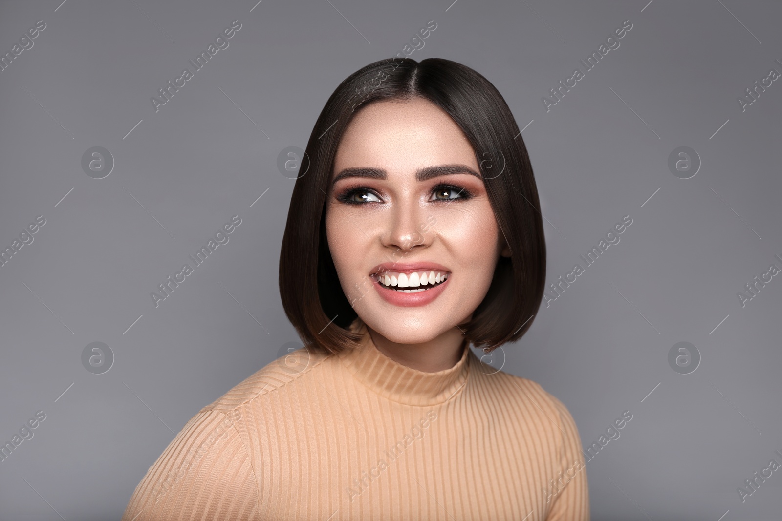 Image of Portrait of pretty young woman with brown hair smiling on grey background