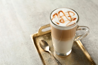 Tray with glass cup of caramel macchiato on table. Space for text