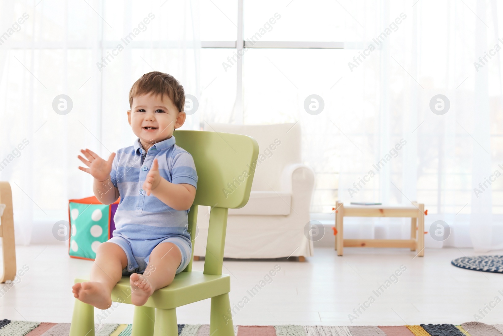 Photo of Cute baby sitting on chair at home