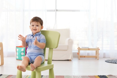 Cute baby sitting on chair at home