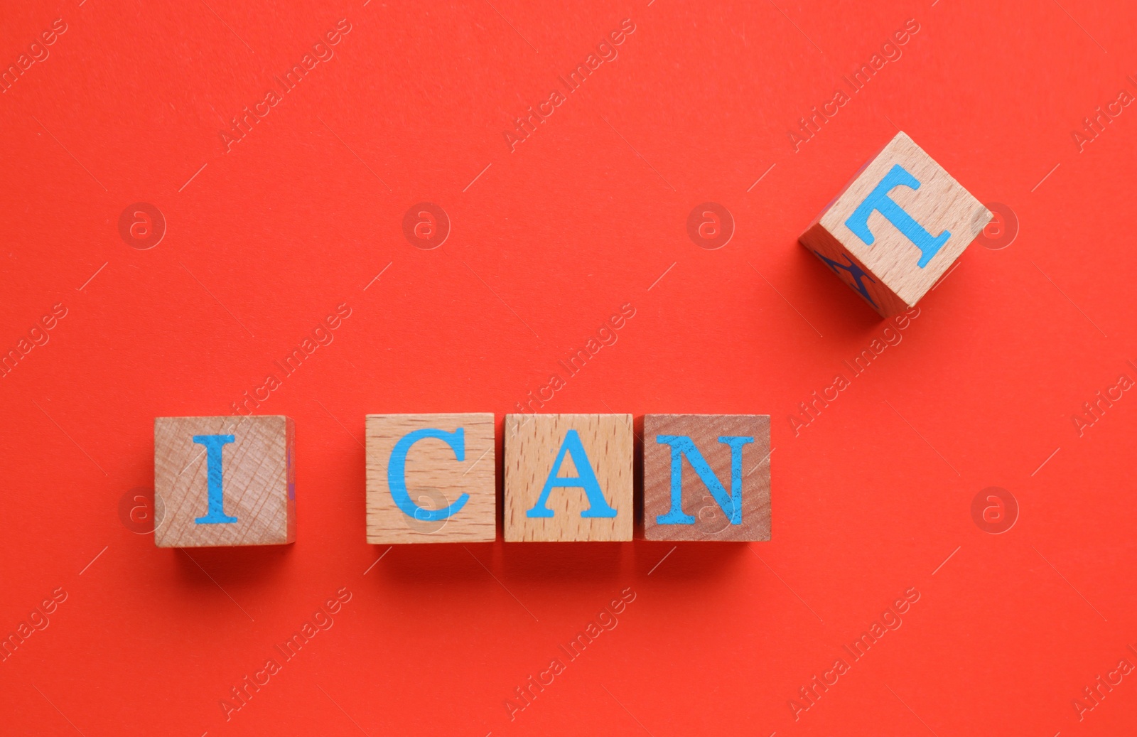 Photo of Motivation concept. Changing phrase from I Can't into I Can by removing cube with letter T on red background, top view