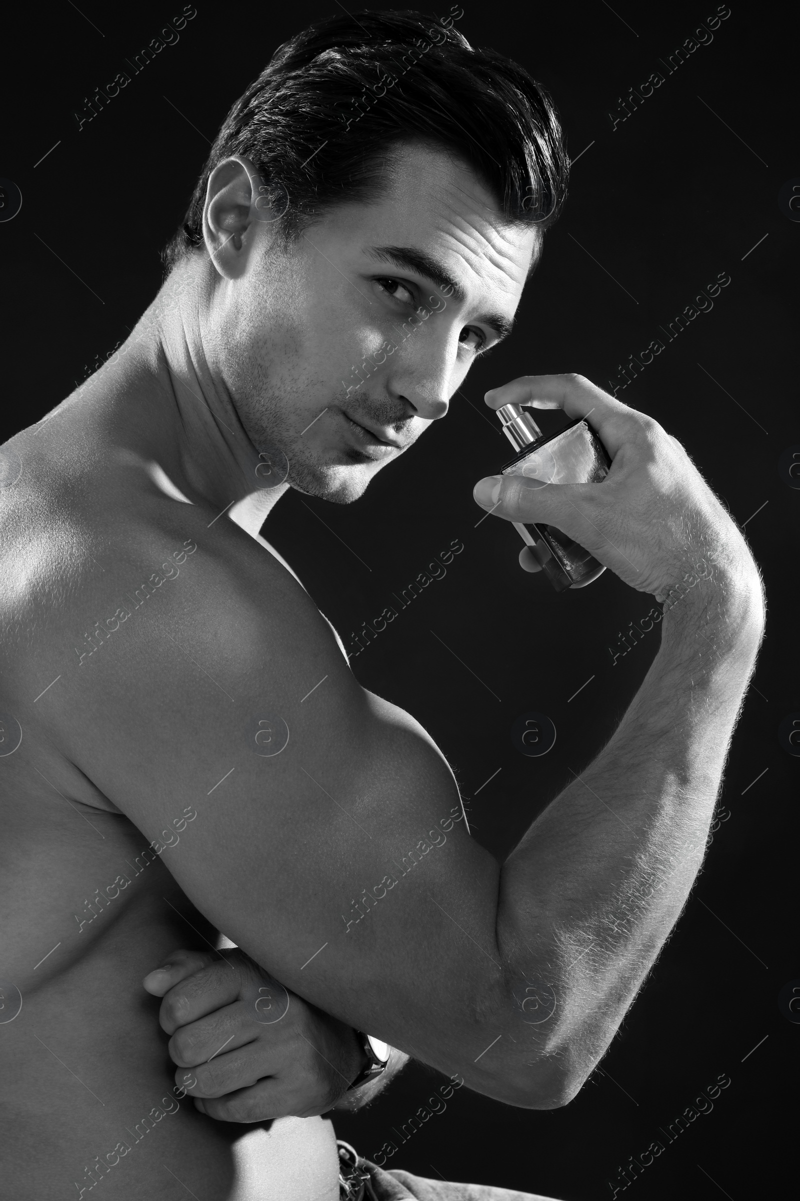 Photo of Handsome young man using perfume, black and white effect