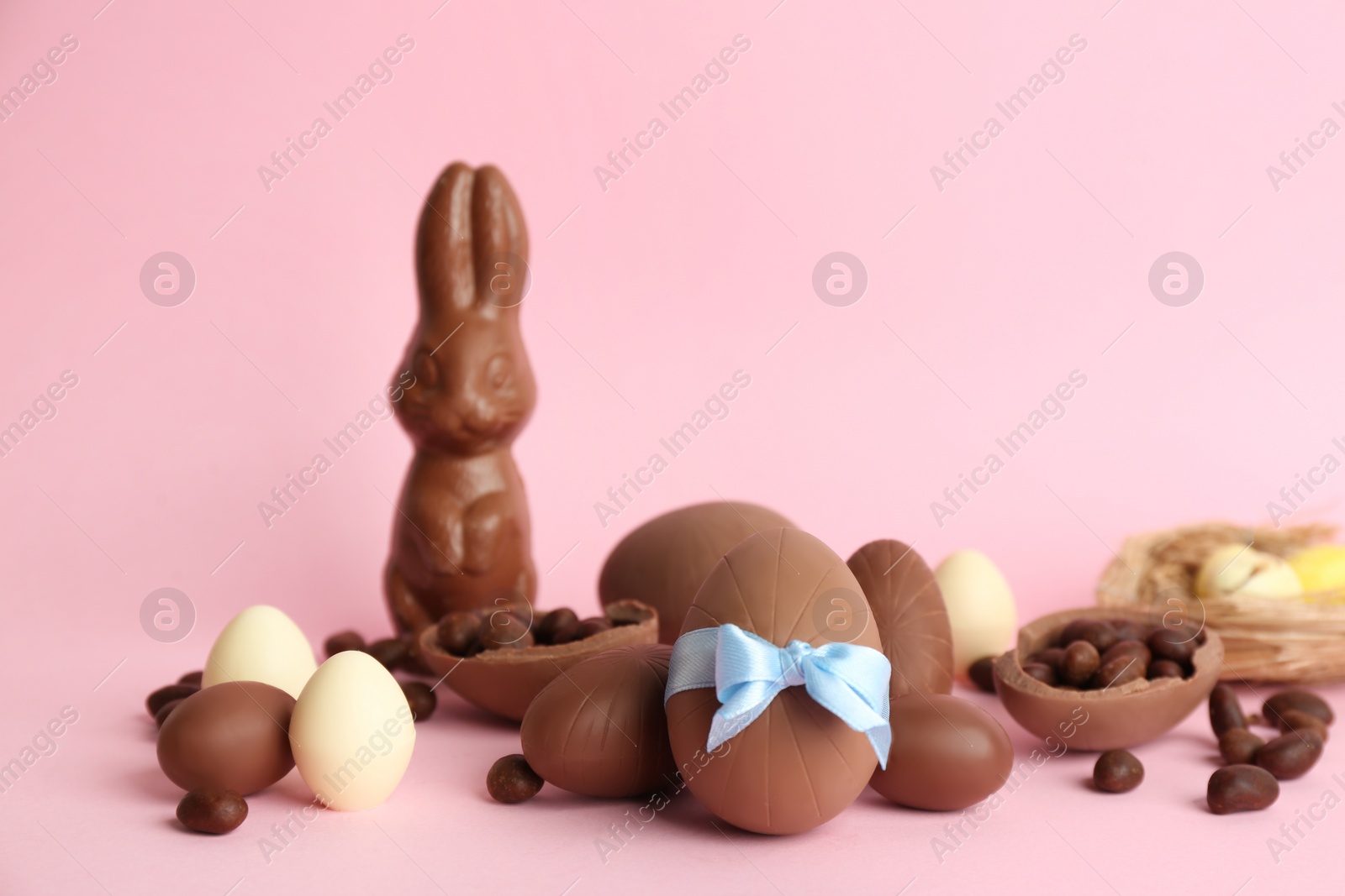 Photo of Sweet chocolate eggs and other candies on pink background