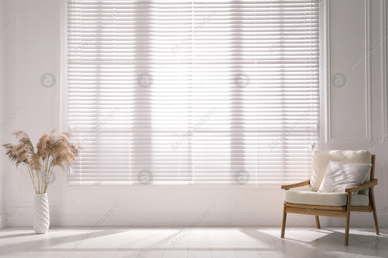 Photo of Cosy armchair and decor near large window with blinds in spacious room. Interior design