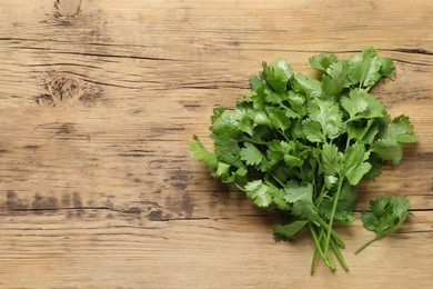 Photo of Fresh green cilantro on wooden table, flat lay. Space for text