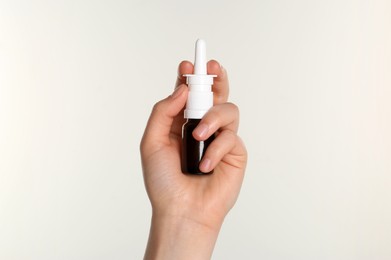 Photo of Woman holding nasal spray on white background, closeup. Space for text