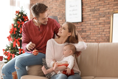 Photo of Happy couple with baby celebrating Christmas together at home