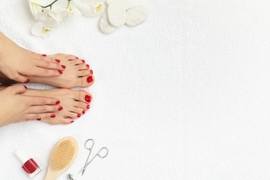 Woman with stylish red toenails after pedicure procedure and orchid flowers on white terry towel, top view. Space for text