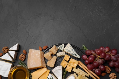 Photo of Cheese plate with honey, grapes and nuts on black table, flat lay. Space for text