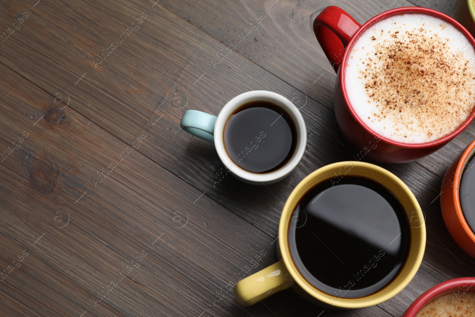 Photo of Many different cups with aromatic hot coffee on wooden table, flat lay. Space for text