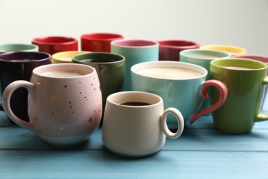 Photo of Many cups of different coffee drinks on light blue wooden table