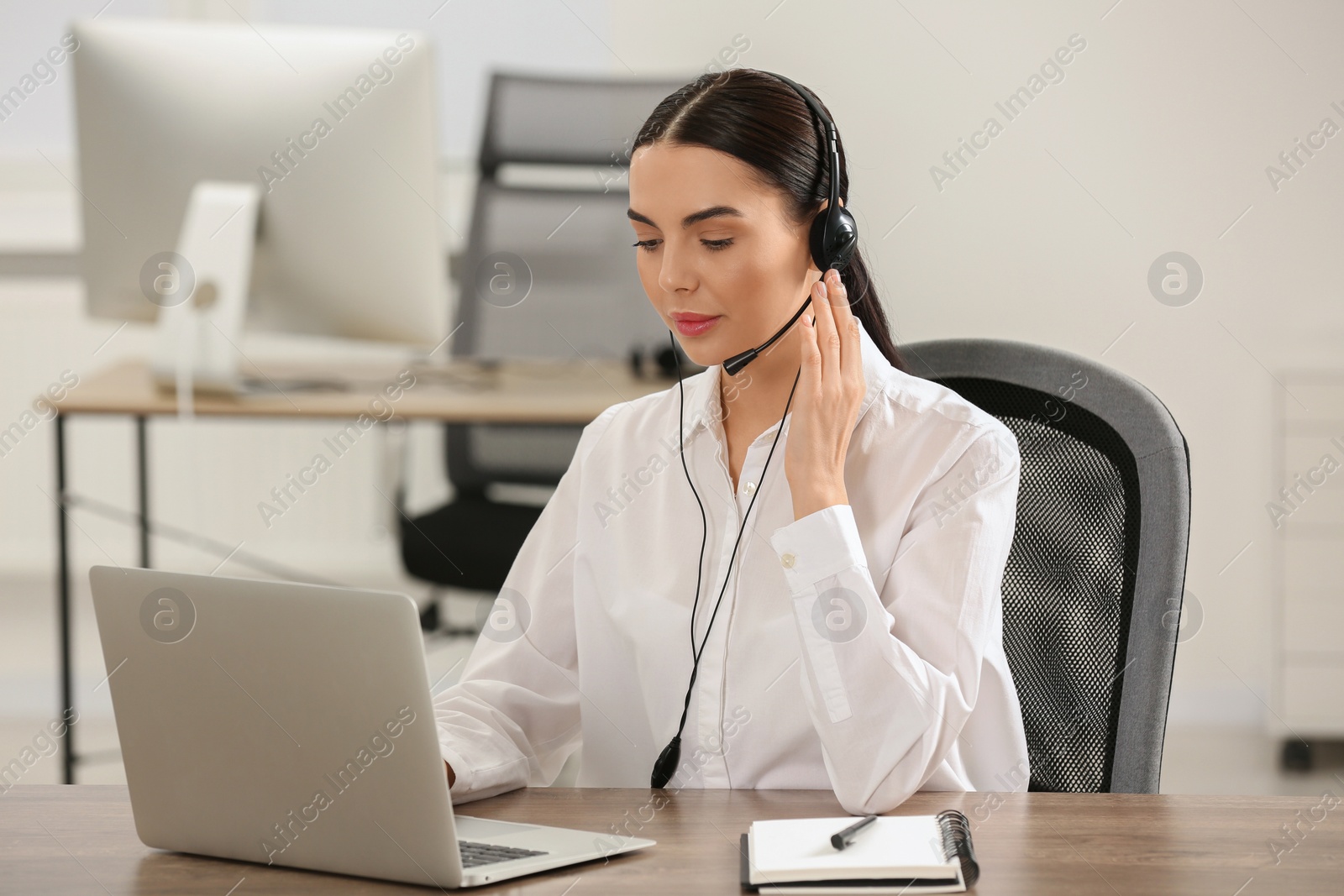 Photo of Hotline operator with headset working on laptop in office