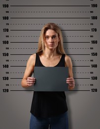 Criminal mugshot. Arrested woman with blank card against height chart