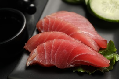 Photo of Tasty sashimi (pieces of fresh raw tuna) on black plate, closeup
