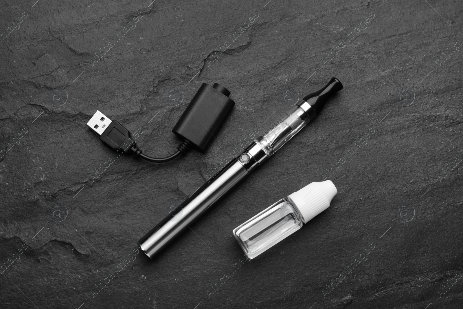 Photo of Electronic smoking device, charger and vaping liquid on black background, flat lay