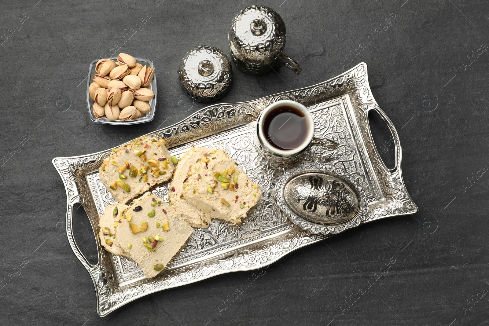 Photo of Tasty halva with pistachios served on grey table, flat lay