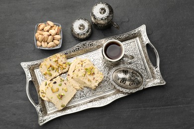 Photo of Tasty halva with pistachios served on grey table, flat lay