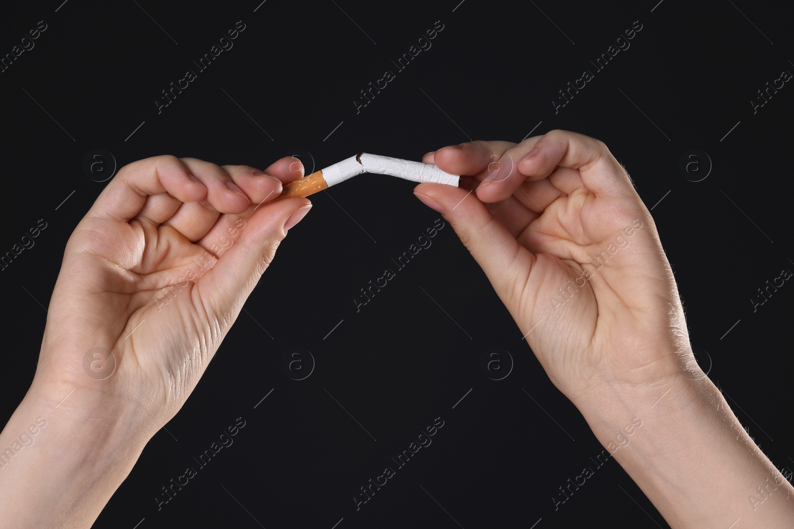 Photo of Stop smoking concept. Woman breaking cigarette on black background, closeup