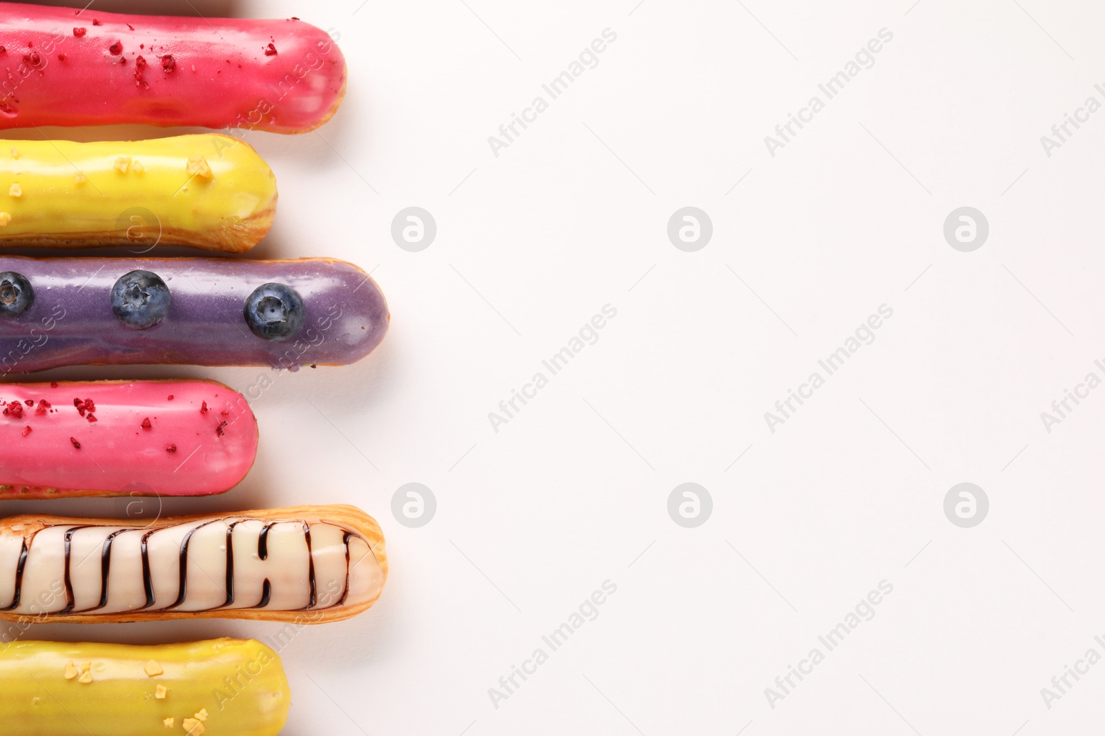 Photo of Delicious eclairs covered with glaze on white background, top view