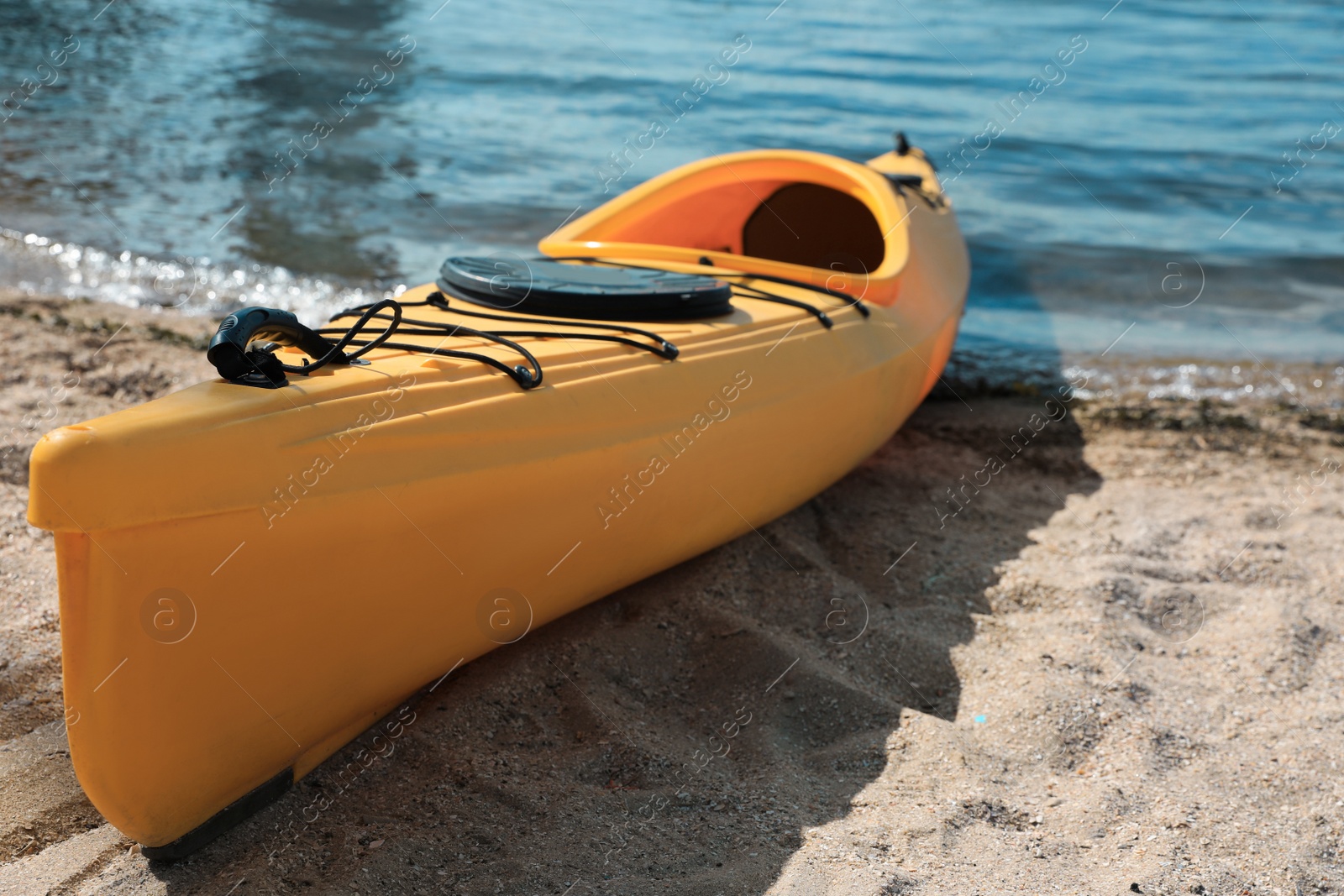 Photo of Yellow kayak on beach near river. Summer camp activity