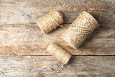 Photo of Natural hemp rope spools and space for text on wooden background, flat lay