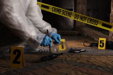 Photo of Criminologist in gloves working with evidences at crime scene outdoors, closeup