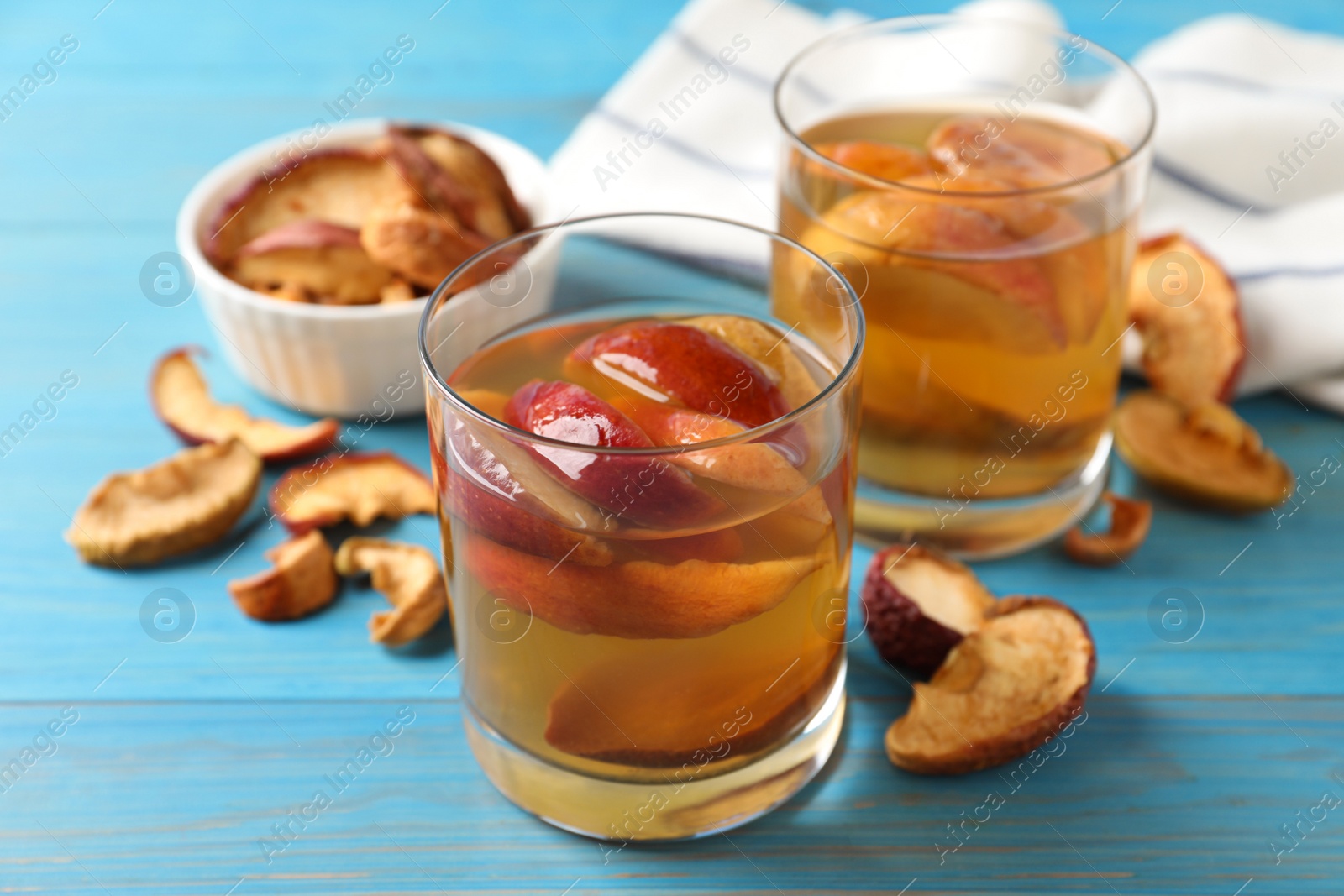 Photo of Delicious compot with dried apple slices on light blue wooden table