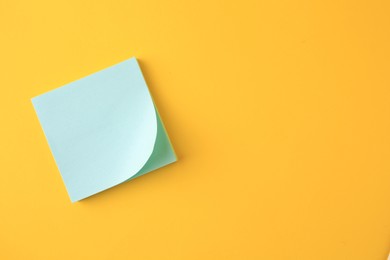 Blank paper note on orange background, top view. Space for text