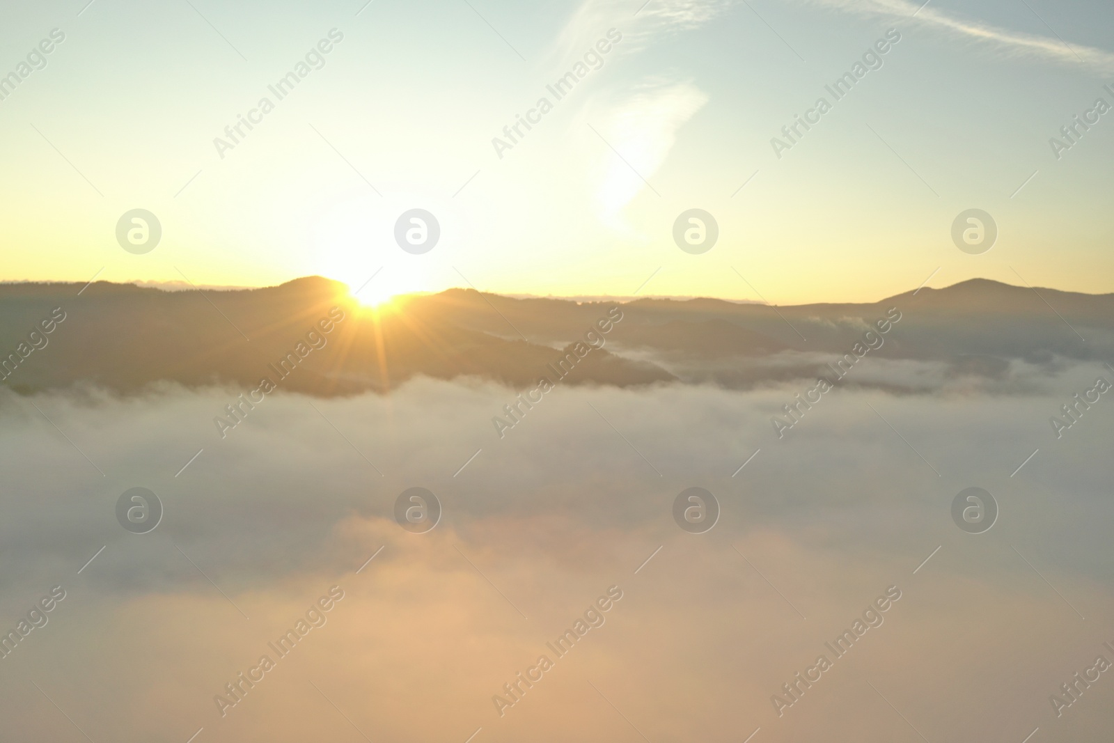 Photo of Aerial view of beautiful mountains covered with fluffy clouds at sunrise