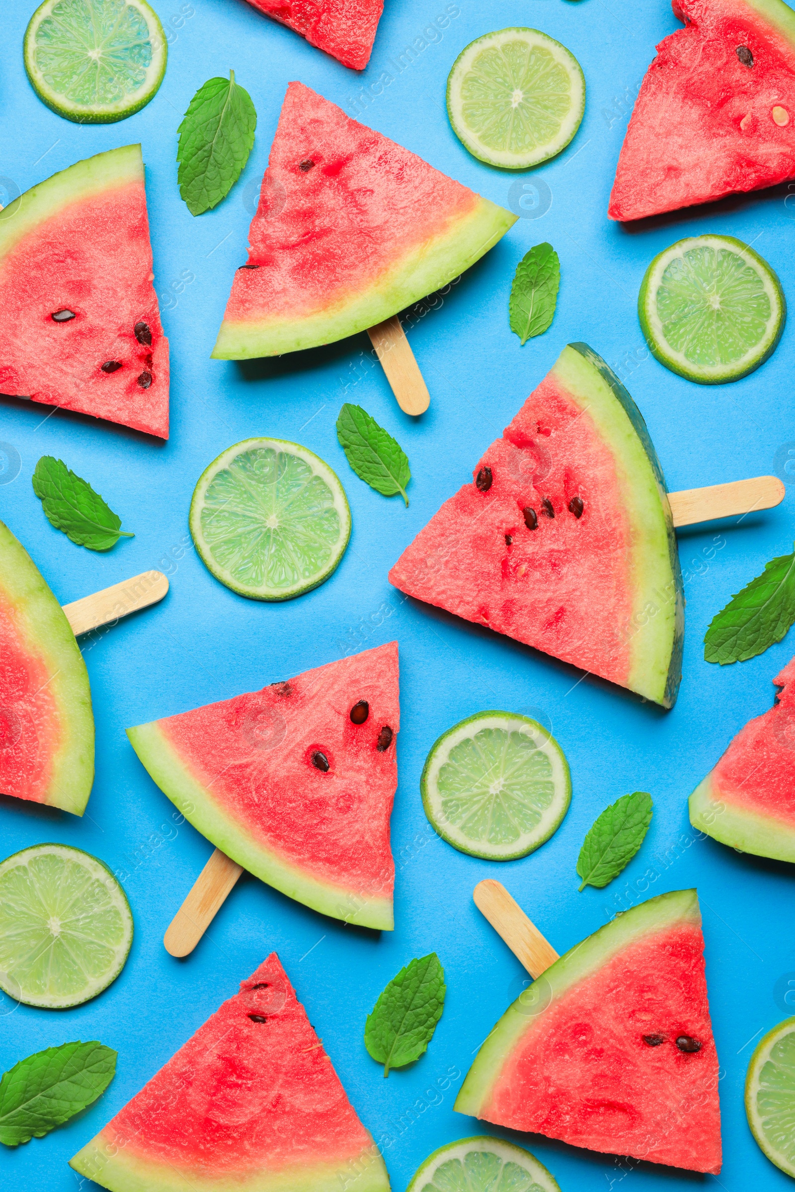 Photo of Tasty sliced watermelon and limes on light blue background, flat lay