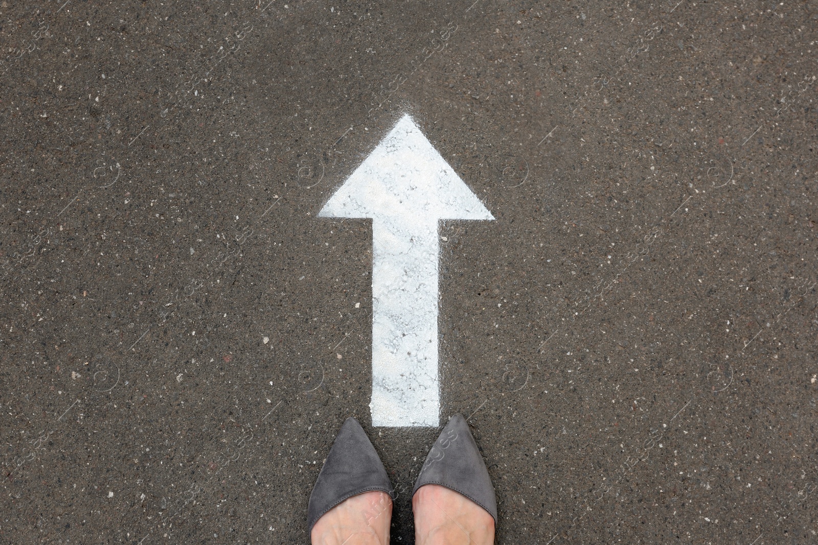 Photo of Woman standing near arrow on asphalt, top view. Choice concept