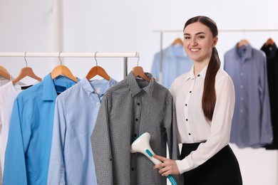 Photo of Woman steaming shirt on hanger in room