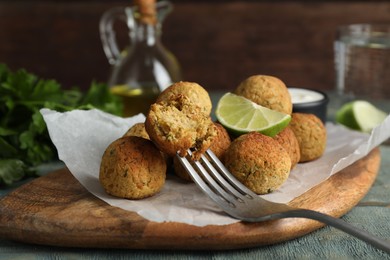 Photo of Delicious falafel balls with lime on light blue wooden table, closeup