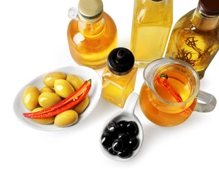 Different cooking oils and olives on white background, above view