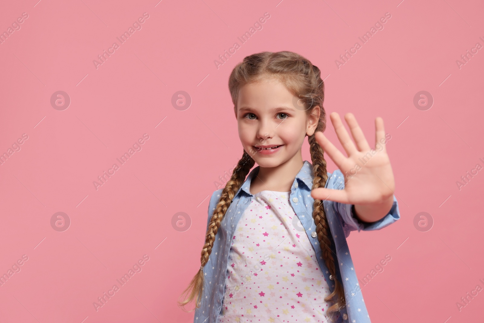 Photo of Cheerful girl giving high five on pink background, space for text
