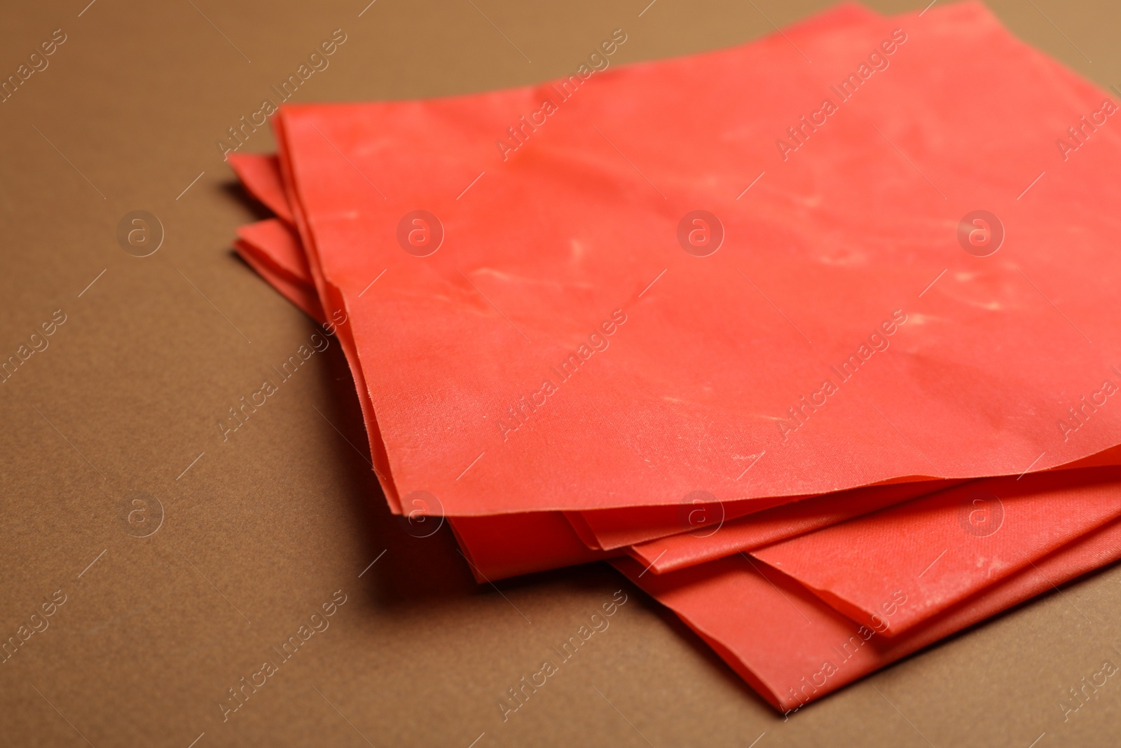 Photo of Red beeswax food wraps on brown background, closeup