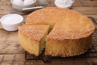 Tasty sponge cake and ingredients on wooden table, closeup