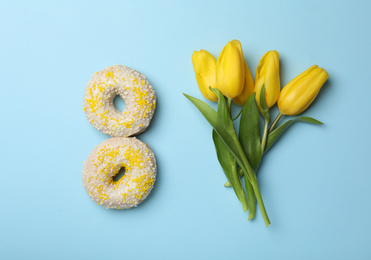 Photo of Flat lay composition with donuts and tulip flowers on light blue background. Women's day