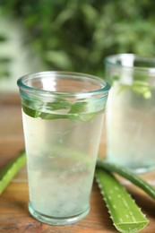 Photo of Fresh aloe drink in glasses and leaves on wooden table