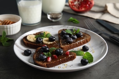 Photo of Different toasts with fruits, blueberries, honey and chia seeds on plate