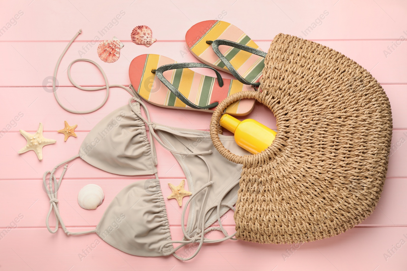 Photo of Stylish bag and beach accessories on pink wooden background, flat lay