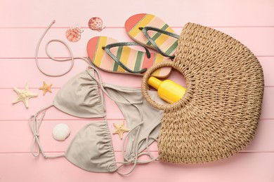 Photo of Stylish bag and beach accessories on pink wooden background, flat lay