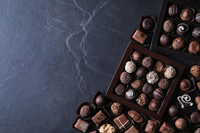 Different tasty chocolate candies on black table, flat lay. Space for text