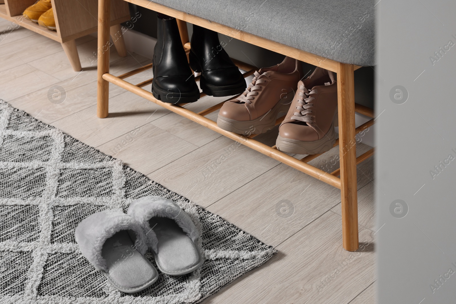 Photo of Shoe storage bench and slippers on floor in hallway. Interior design