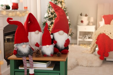 Cute Christmas gnomes on wooden table in room with festive decorations. Space for text