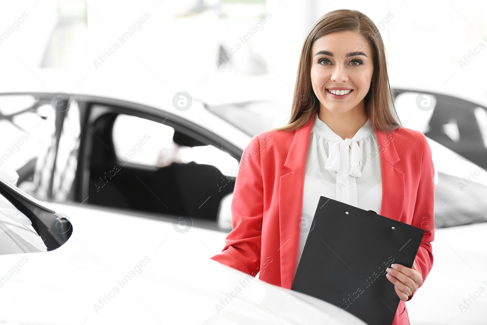 Photo of Young woman with clipboard in car salon